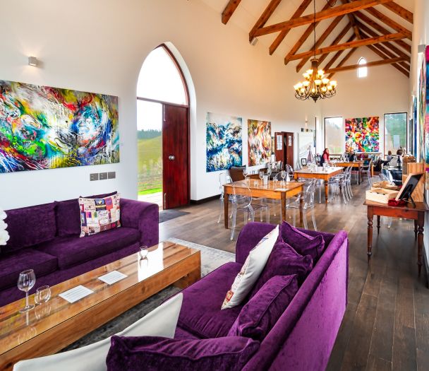 restaurant tables in a building with vaulted ceilings and purple velvet chairs